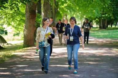 Two guests smiling and walking in a park at myConf 2024.